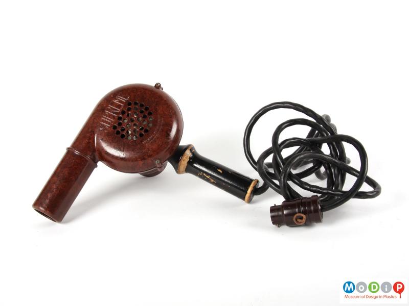 Side view of a hairdryer showing the wooden handle, the cable, and the plug.
