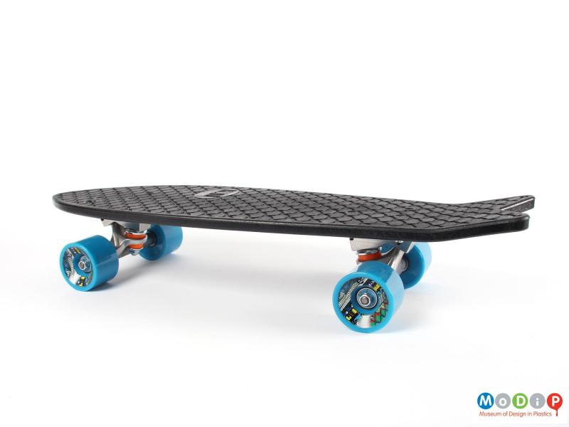 Side view of a skateboard showing the blue wheels.