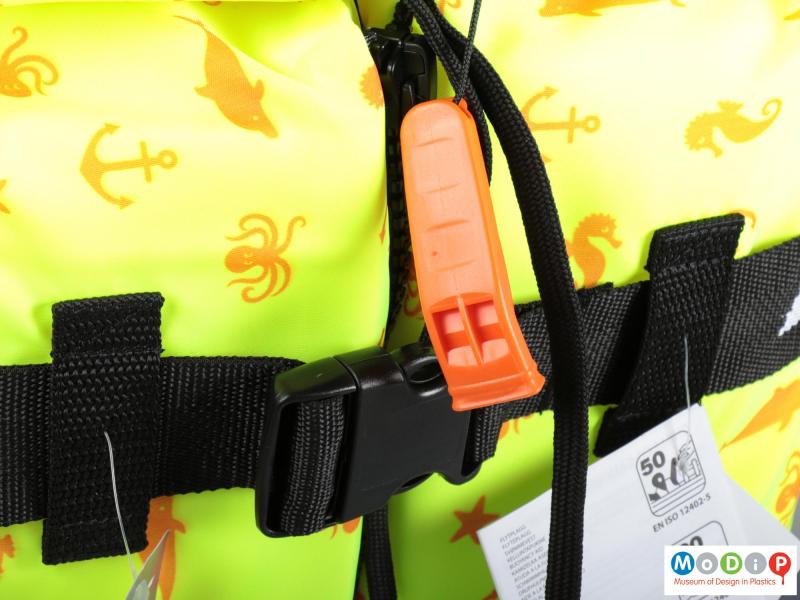 Close view of a life jacket showing the whistle and buckle.