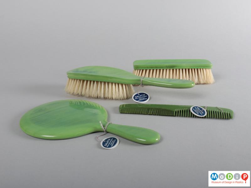 Side view of a grooming set showing the two brushes, the comb and the mirror.