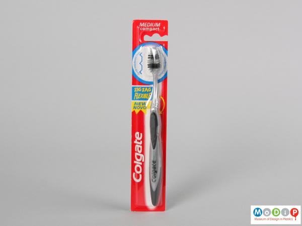 Front view of a packaged toothbrush showing the ergonomic shape of the handle and head.