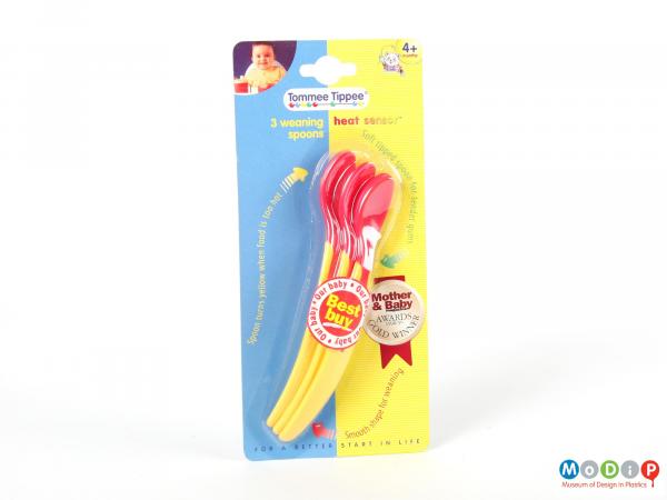 Front view of a packaged set of Tommee Tippee spoons showing the yellow handles and red bowls.