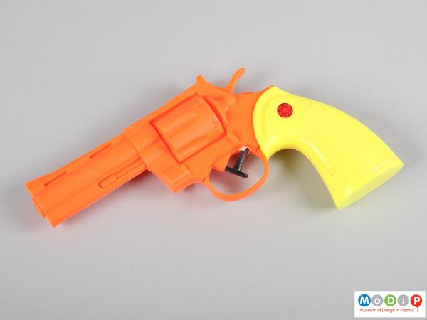 Side view of a water pistol showing the yellow handle and orange body.