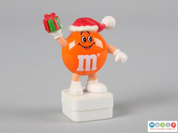 Front view of an orange M&M figure showing the smiling face and the limbs.