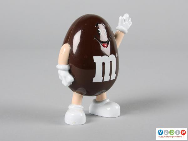 Side view of a brown M&M figure showing the smiling face and the limbs.