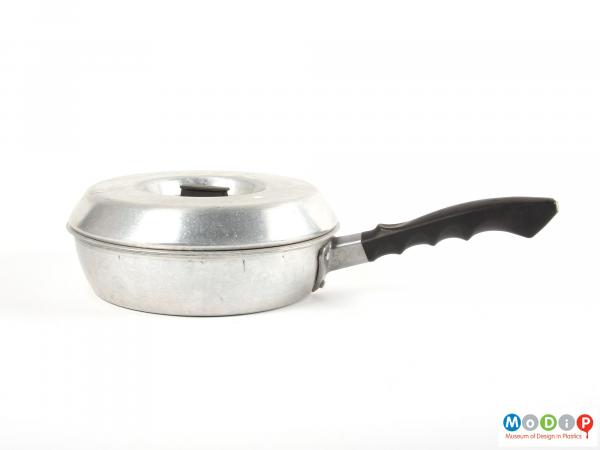 Side view of an egg poacher pan showing the handle with ergonomic grip.