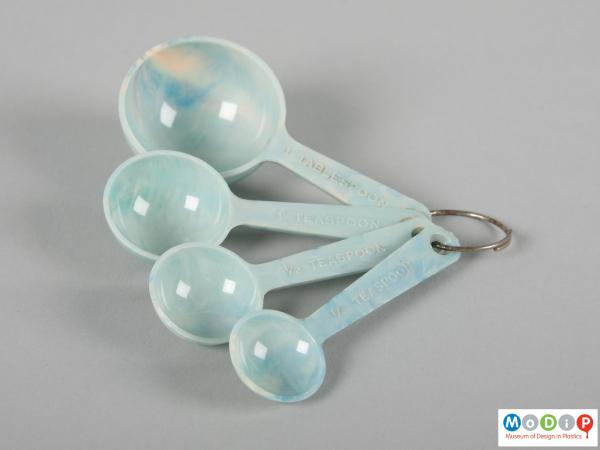 Side view of a set of measuring spoons showing the metal ring and the different sized spoons.