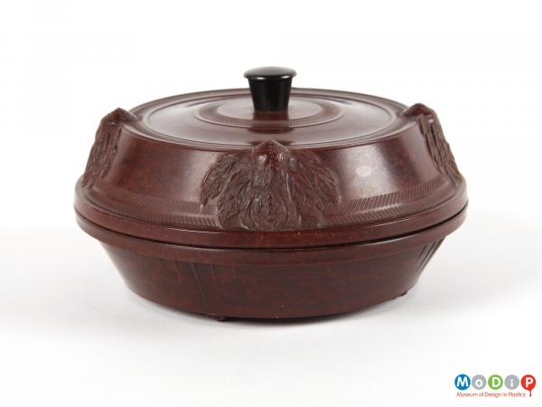 Side view of a lidded pot showing the moulded decoration on the lid.