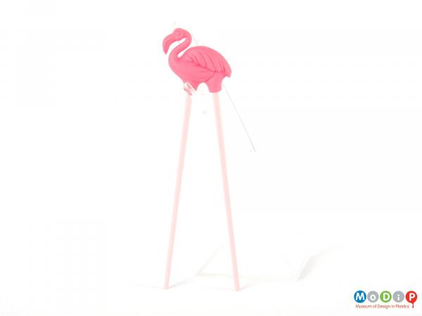 Side view of a pair of chopsticks showing the flamingo shaped topper.