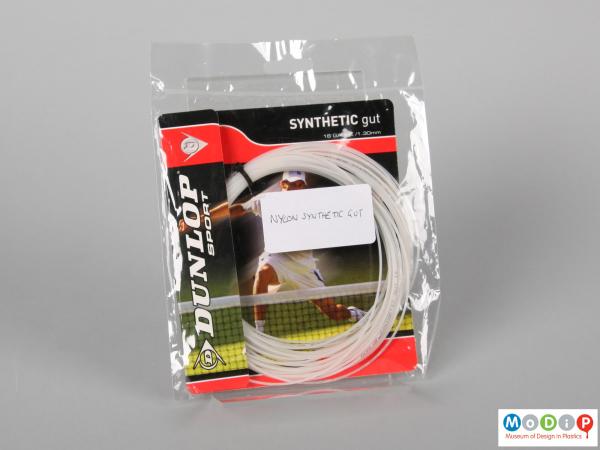 Front view of a length of tennis racket string showing the packaging.