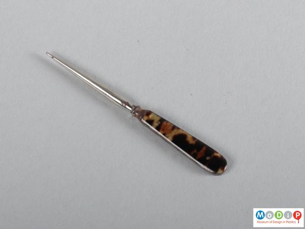 Side view of an awl showing the metal point and tortoiseshell effect handle leaves.