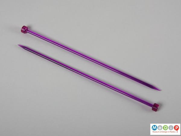 Side view of a pair of knitting needles showing the plain shaft and head.