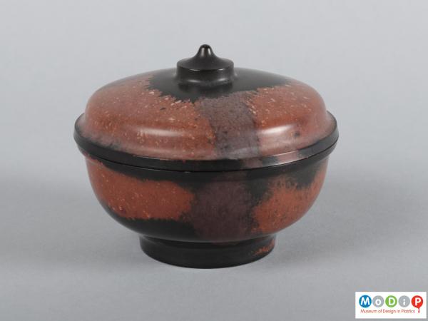 Side view of a lidded dish showing the integral foot and finial.