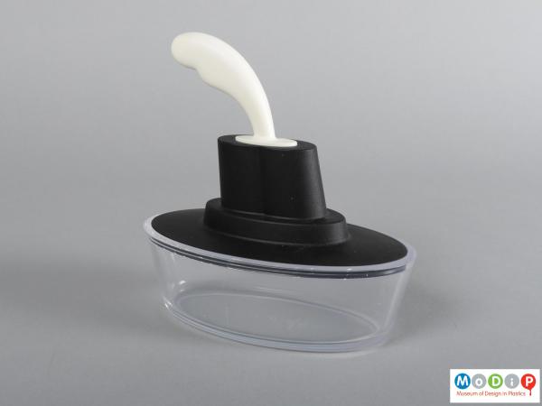 Side view of a butter dish showing the clear base, black cover, and white knife handle.