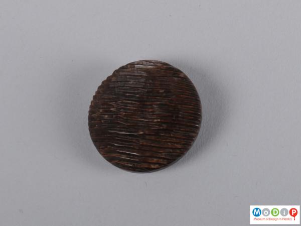 Front view of a button showing the circular shape and cut design.