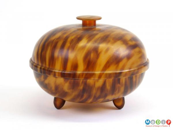 Side view of a tortoiseshell effect powder bowl showing two feet