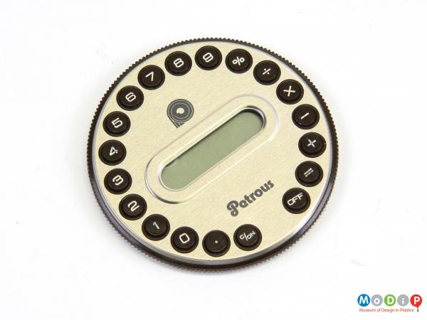Top view of a Petrous PRMC-1 calculator showing the round buttons running around the edge, the display panel in the middle and the textured grip around the side.