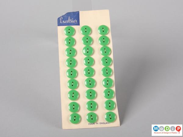 Front view of an Excelsior button with three columns of small green buttons.