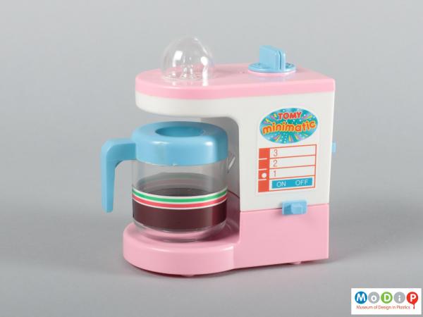 Front view of a toy coffee maker showing the adhesive sticker, and the on / off switch.