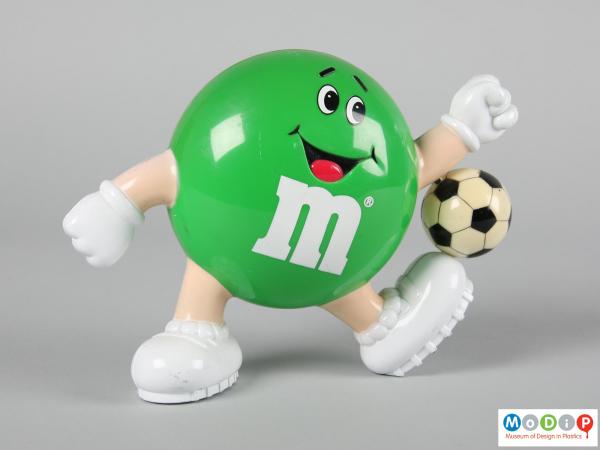front view of a green M&M figure showing the smiling face and limbs.