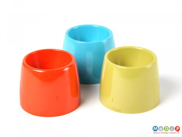Side view of a plain orange egg cup along side the green and blue egg cups which match it.