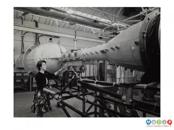 Scanned image showing a woman looking at a wind tunnel.