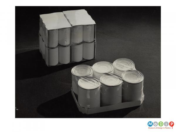Scanned image showing shrink wrapped crates of cans.