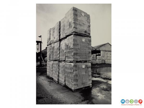 Scanned image showing piles of pallets loded with bricks and shrink wrapped in plastic.