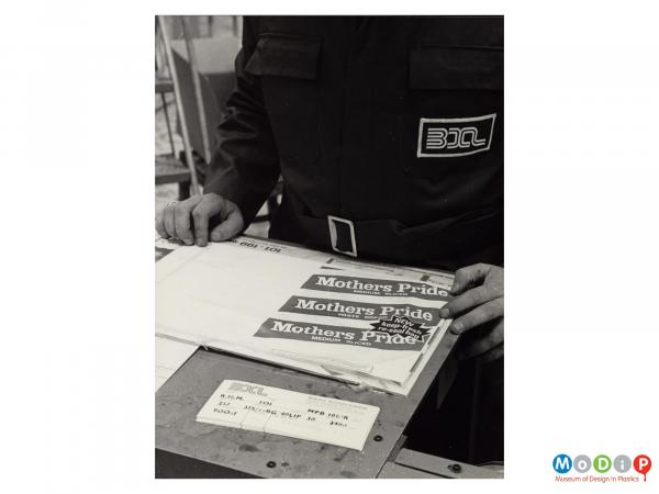 Scanned image showing a male worker checking the quality of a bread bag.