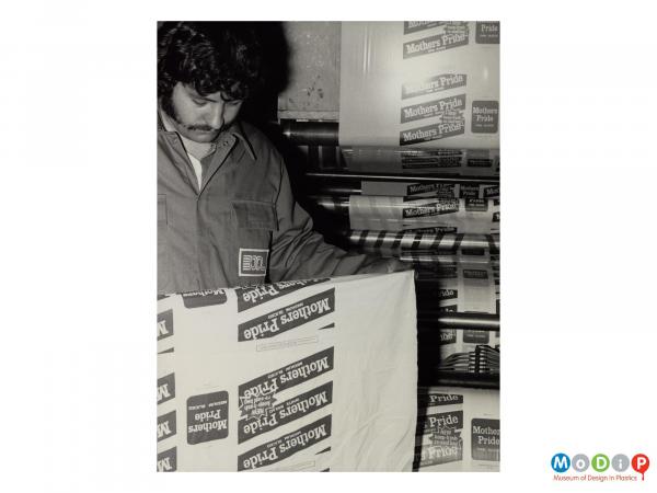 Scanned image showing a male worker checking the print quality of a bread bag.