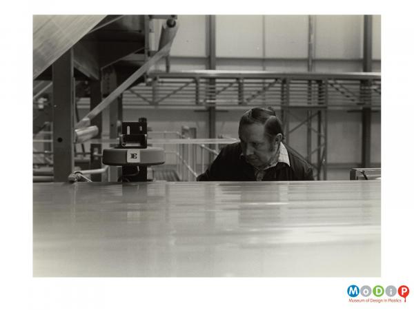 Scanned image showing a man operating a lazer to measure the quality of material.