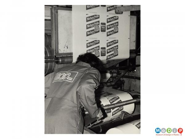 Scanned image showing a male worker checking machinery producing bread bags.