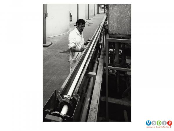 Scanned image showing a male worker at an extrusion production line.