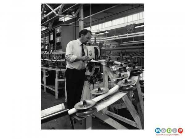 Scanned image showing a male employee inspecting a cable.