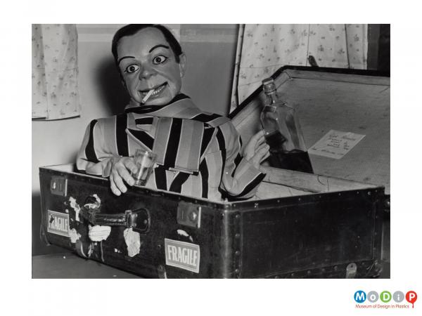 Scanned image showing a puppet in a suitcase.