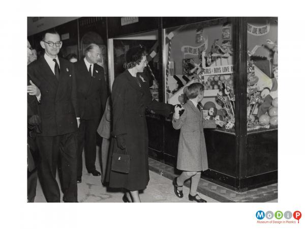 Scanned image showing visitors walking past a display of products.