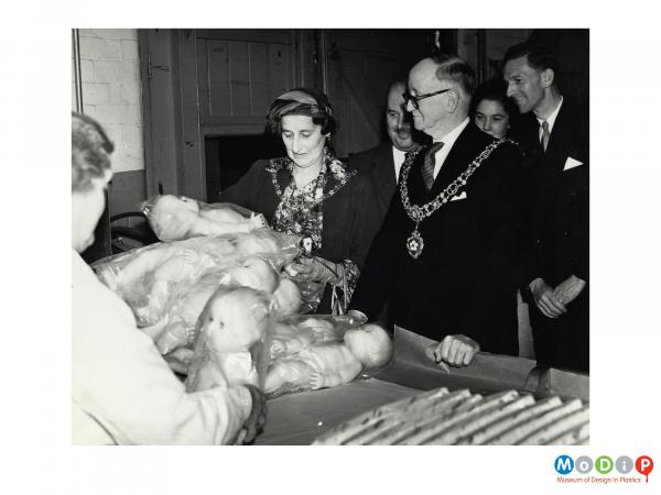 Scanned image showing a Mayoral group looking at dolls.