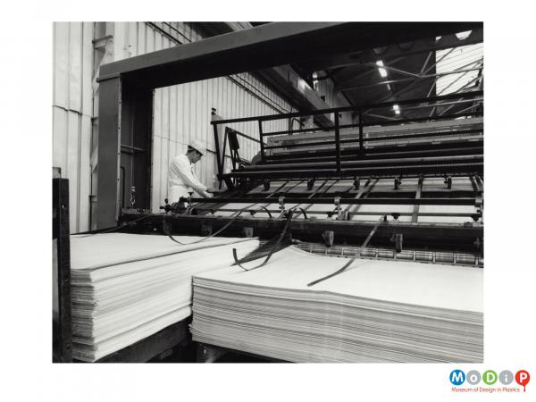 Scanned image showing a male worker at a machine for sheet production.