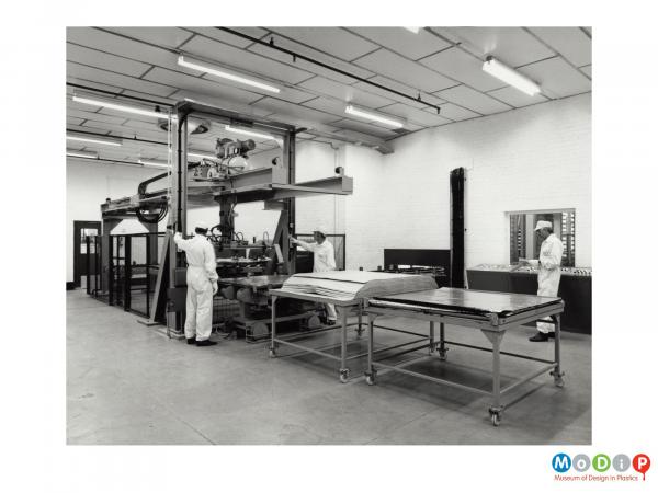 Scanned image showing workers at a sheet production machine.