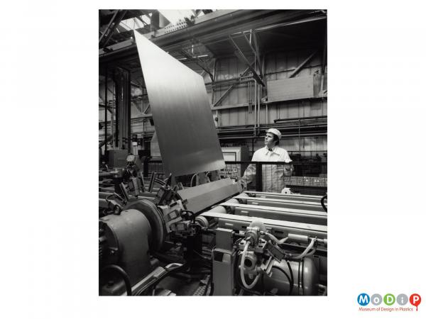 Scanned image showing a male worker at a sheet production line.