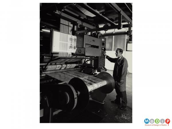 Scanned image showing a male worker operating a printing machine.