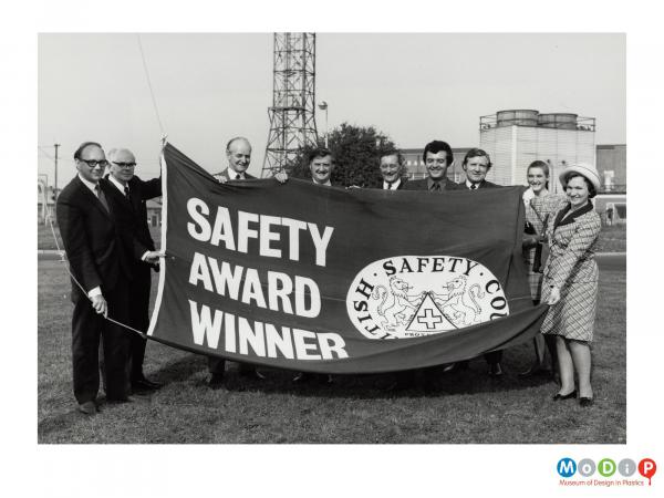 Scanned image showing the presentation of a safety award flag.