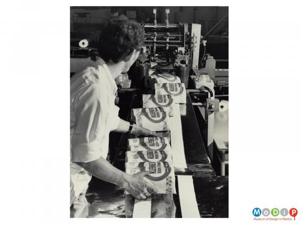 Scanned image showing packets of kitchen towels coming off a production line.