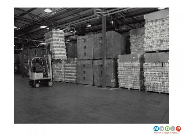 Scanned image showing a fork lift truck moving loaded pallets.