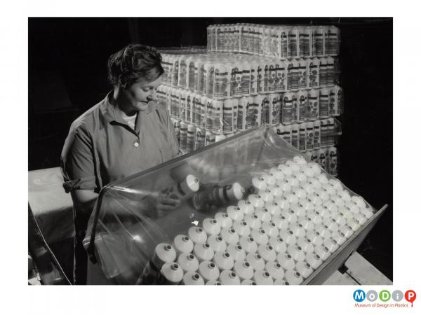 Scanned image showing a woman packing bottles.