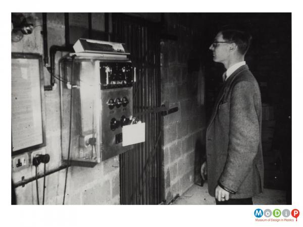 Scanned image showing a man looking at an electrical device.