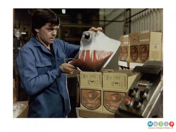 Scanned image showing a employee placing a wine bag into a box.