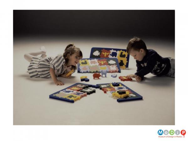 Scanned image showing two children playing with a puzzle toy on the floor.
