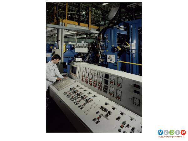 Scanned image showing a male worker at a control panel.