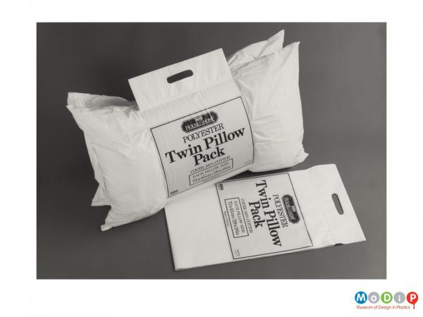 Scanned image showing two pillows in carry-home packaging.